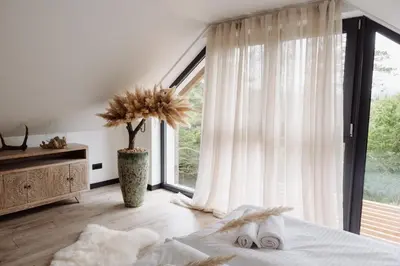 a large bed in a room with a large window at W szczerym lesie - Domek z sauną i jacuzzi w lesie nad Jeziorem Mucharskim in Dąbrówka