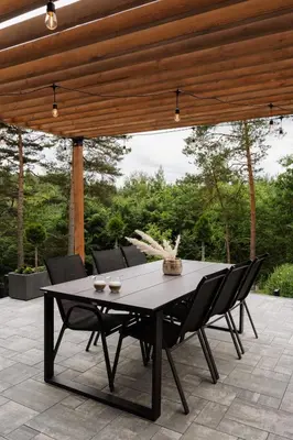 a black table and chairs on a patio at W szczerym lesie - Domek z sauną i jacuzzi w lesie nad Jeziorem Mucharskim in Dąbrówka