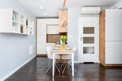 a kitchen with white cabinets and a table and chairs at Mieszkanie na Groblach in Kraków