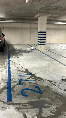 an empty parking garage with blue writing on the ground at Mama's Home Krakow in Kraków