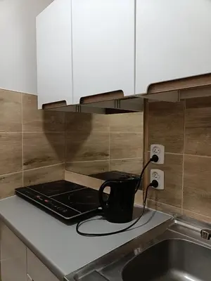 a kitchen with white cabinets and a sink and a stool at Pokoje Krakow Plus in Kraków