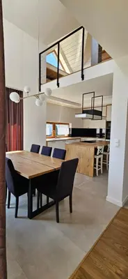 a dining room and kitchen with a wooden table and chairs at Villa Kozikowka lake and forest near Krakow and Wieliczka in Ulesie