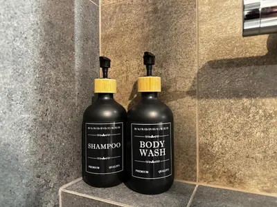 two black bottles of body wash sitting on a wall at Salsa Apartament in Kraków