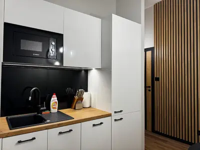 a kitchen with white cabinets and a sink and a microwave at Salsa Apartament in Kraków