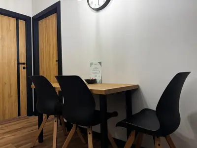 a table with black chairs and a clock on the wall at Salsa Apartament in Kraków
