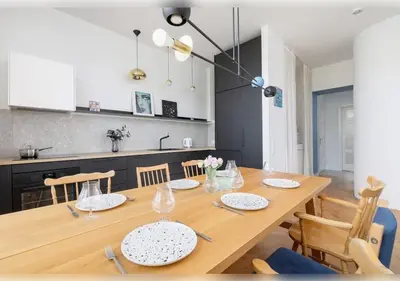a dining room with a wooden table and a kitchen at Apartament Rodzinny w Centrum Krakowa by Noclegi Renters in Kraków