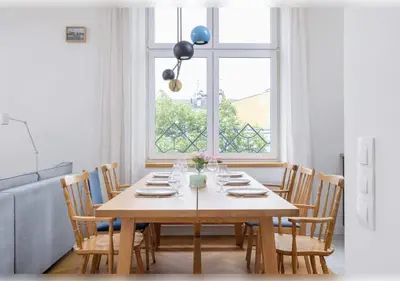 a dining room table with chairs and a large window at Apartament Rodzinny w Centrum Krakowa by Noclegi Renters in Kraków