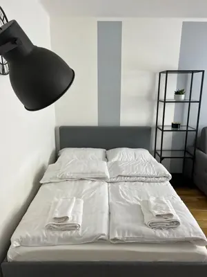 a bed with white sheets and a black lamp at Tomasza 25 Main Square Apartment in Kraków