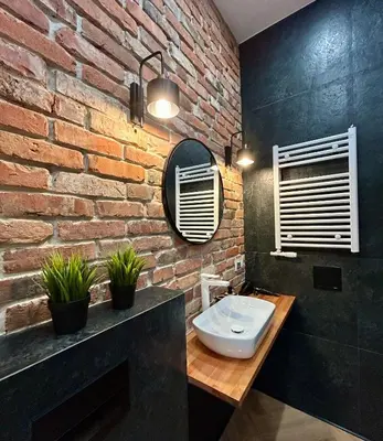 a bathroom with a brick wall and a sink at Sky Mirror jacuzzi in Kraków