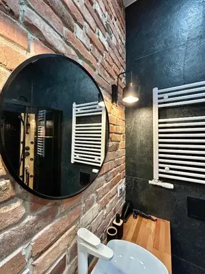 a bathroom with a mirror on a brick wall at Sky Mirror jacuzzi in Kraków