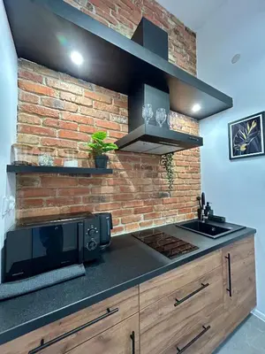 a kitchen with a microwave and a brick wall at Sky Mirror jacuzzi in Kraków