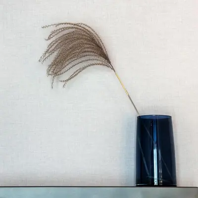 a blue vase with a feather sticking out of it at Ironique by MB Apartments in Kraków