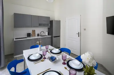 a white table with blue chairs in a kitchen at The Royal Patch Aparthotel in Kraków