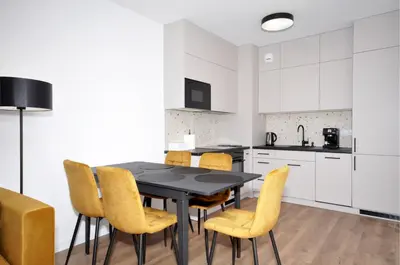 a kitchen with a black table and yellow chairs at Myśliwska Solar Garden Premium Apartment Wawelofts - free Garage in Kraków