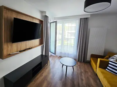 a living room with a tv and a couch and a table at Myśliwska Solar Garden Premium Apartment Wawelofts - free Garage in Kraków