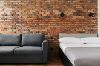 a bed and a couch in front of a brick wall at Native Apartments Długa 24I3 in Kraków
