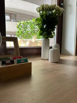 a vase of flowers sitting on a floor next to a window at Kaskada Apartment in Kraków