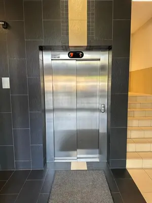 a metal elevator in a room with a tile wall at Kaskada Apartment in Kraków