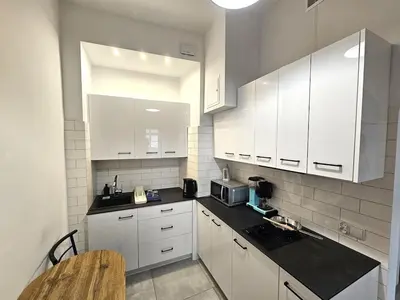 a kitchen with white cabinets and a black counter top at Pawia Apartments Old Town in Kraków