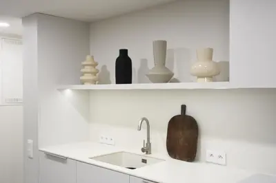a white kitchen with a sink and shelves with vases at Stradom Studio in Kraków