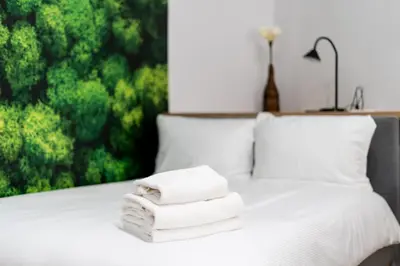 a pile of towels on a bed with a window at Cozy studio - Starowislna 54 Street in Kraków