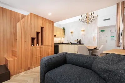 a living room with a couch and a kitchen at Urban Light Apartment - 3' Main Square - by Upstairs in Kraków