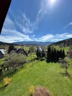 a green field with trees and houses in the distance at Dom pod Cuplikiem in Zawoja