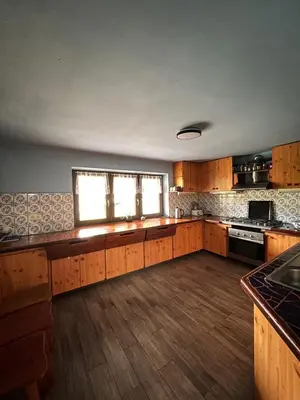 a large kitchen with wooden cabinets and a window at Dom pod Cuplikiem in Zawoja