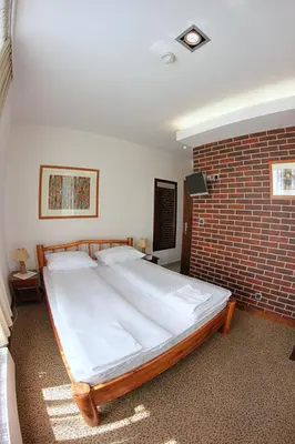 a large bed in a room with a brick wall at Hotel Olecki in Oświęcim