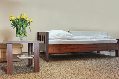 a bed with a vase of yellow flowers on a table at Hotel Olecki in Oświęcim