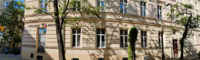 a white building with a tree in front of it at Apartament Niebieski in Kraków