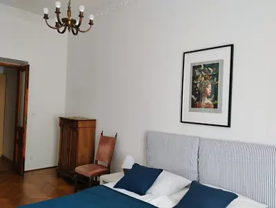 a bedroom with a bed and a chair and a chandelier at Apartament Niebieski in Kraków