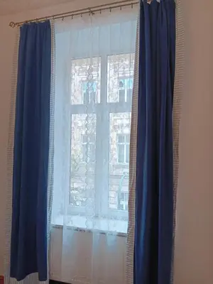 a window with blue curtains in a room at Apartament Niebieski in Kraków