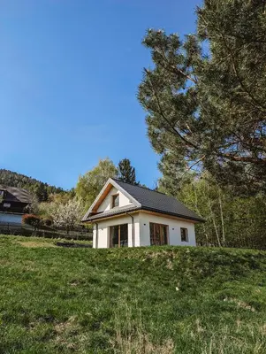 a small white house on top of a grassy hill at Beskidzka Kraina in Porąbka