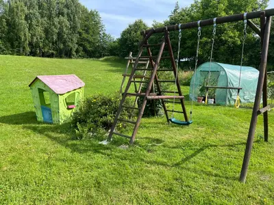a swing set and a house in a field at Wiejska Przystań blisko Energylandii in Po”łwieś