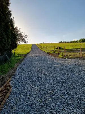 a gravel road in a field with a fence at Wiśniowe Zacisze - Agroturystyka in Sułkowice