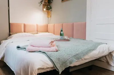 a pink bed with a blanket and a bottle on it at Celna Corner in Kraków