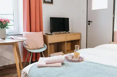 a room with a bed and a tv and a chair at Celna Corner in Kraków