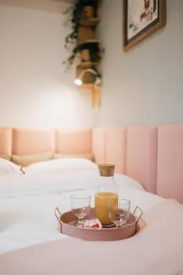 a tray with a bottle of juice and two glasses on a bed at Celna Corner in Kraków