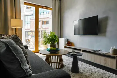 a living room with a couch and a tv on a wall at Cosy Blue Cracow Apartment in Kraków