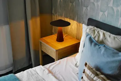 a lamp on a night stand next to a bed at Cosy Blue Cracow Apartment in Kraków