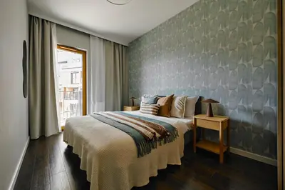 a bedroom with a large bed and a wall at Cosy Blue Cracow Apartment in Kraków