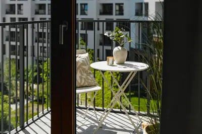 a table and chairs on a balcony with a vase on it at Cosy Blue Cracow Apartment in Kraków