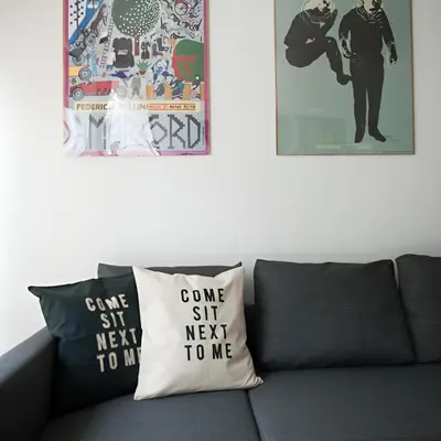 a couch with two pillows that say come sit next to me at Kopernik-us 2 rooms - Old Town in Kraków