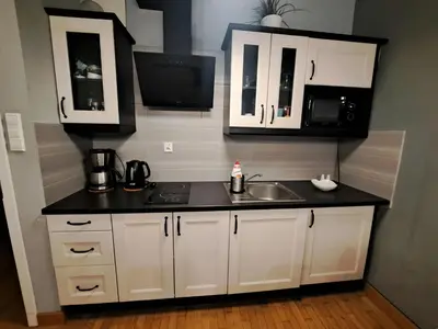 a kitchen with white cabinets and a sink and a microwave at Kopernik-us 2 rooms - Old Town in Kraków