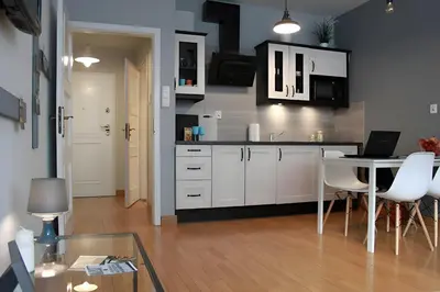 a kitchen with white cabinets and a table with a laptop at Kopernik-us 2 rooms - Old Town in Kraków