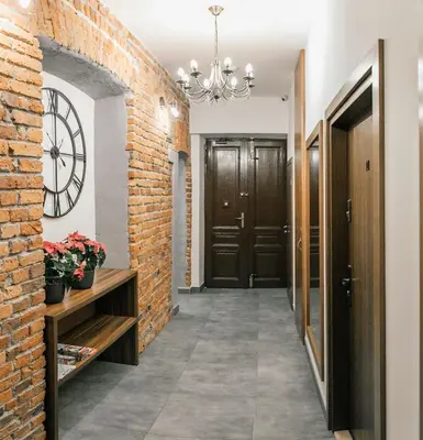 a hallway with a brick wall and a chandelier at Apartamenty Bonerowska 5 in Kraków