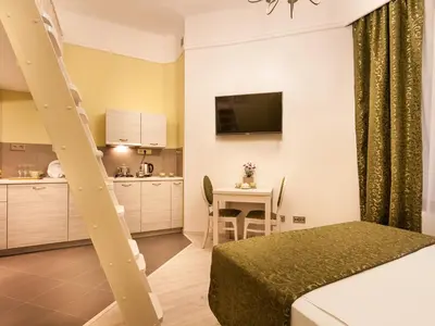 a bedroom with a bed and a kitchen with a table at Apartamenty Bonerowska 5 in Kraków