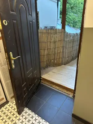 an open door with a tile floor and a wooden fence at Wolnica Apartament 1 in Kraków