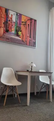 a desk with a white chair and a table with a lamp at Cozy Apartment 4A in Kraków
